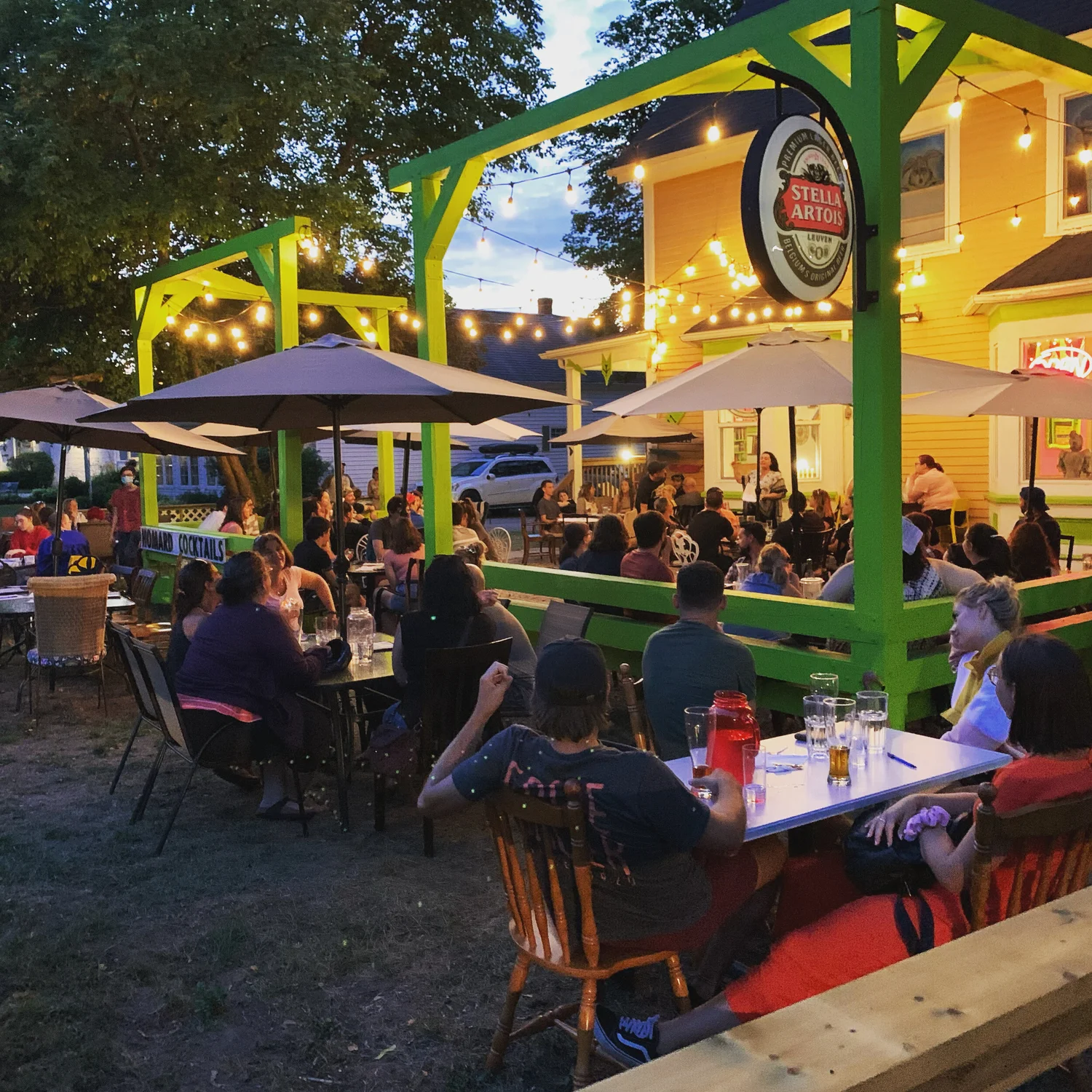 Diners on the string-lit green pergola patio at night